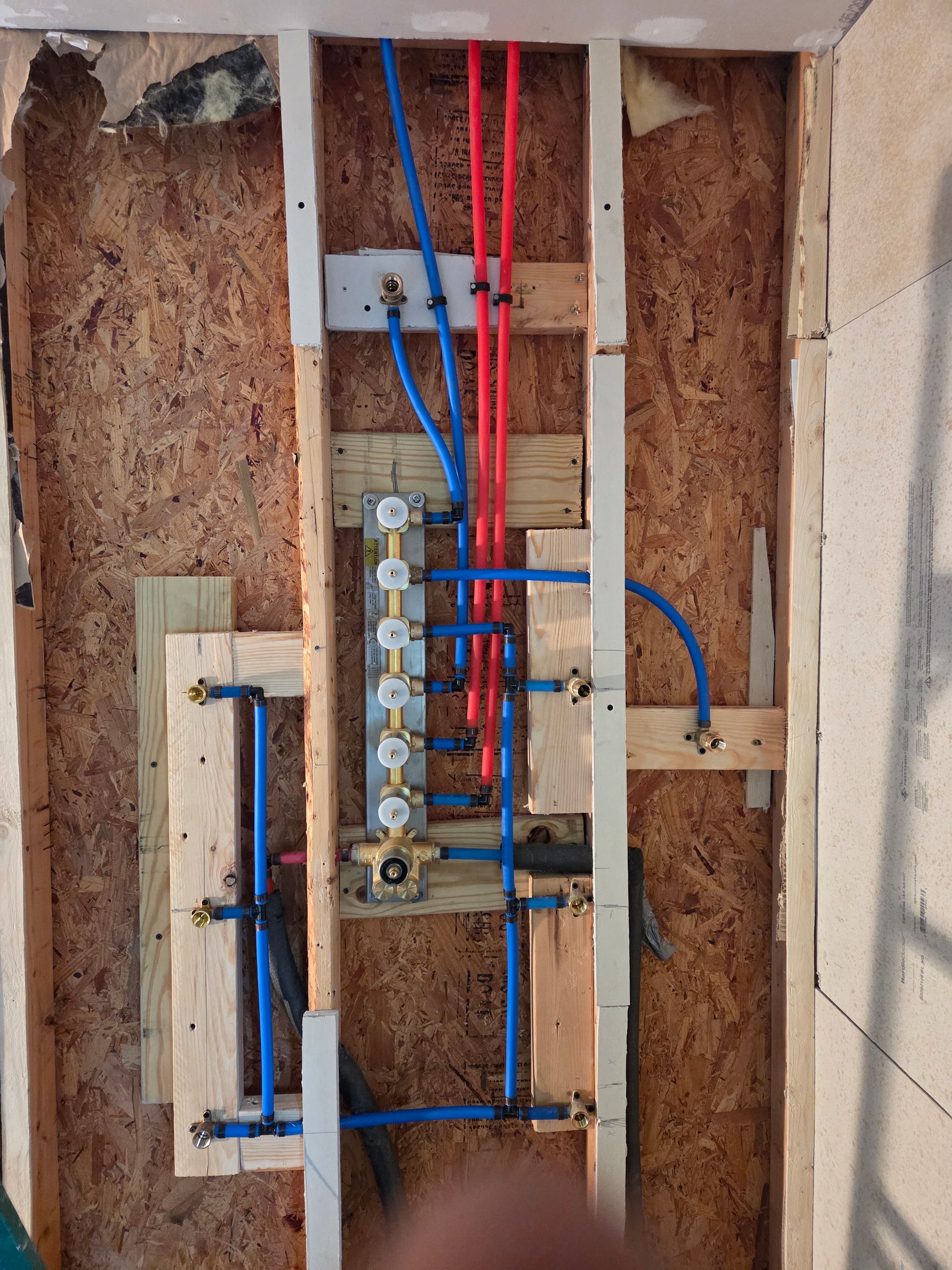 Open electrical panel with exposed blue and red wires in a wall cavity