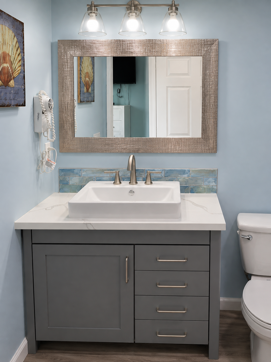 Modern bathroom vanity with gray cabinet, white sink, mirror, and light blue walls