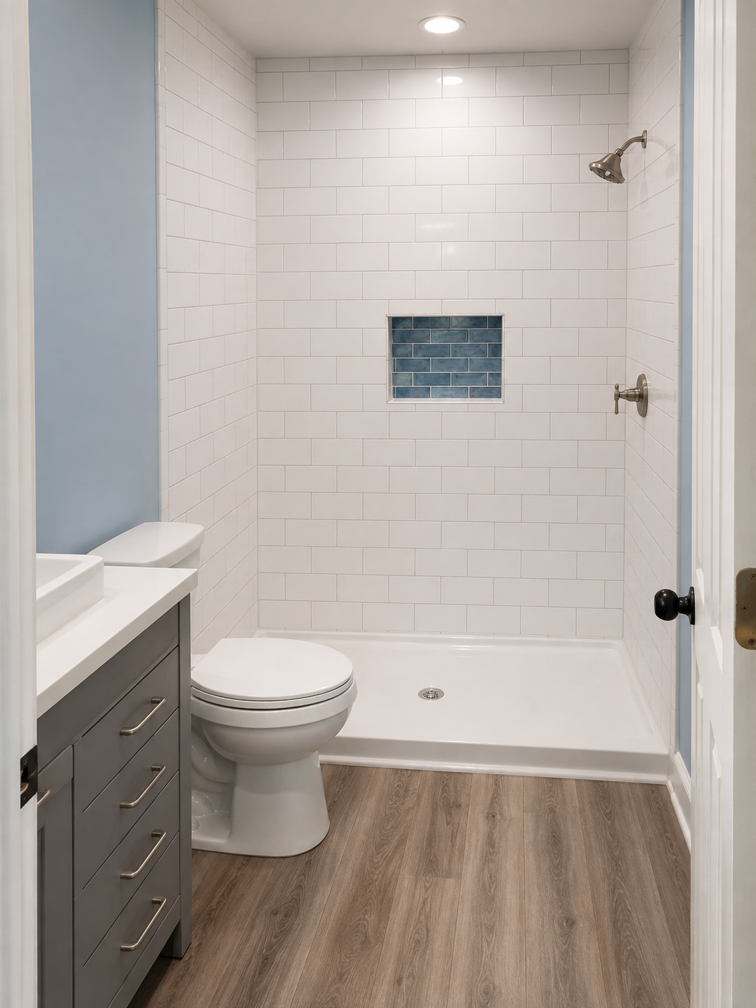 Modern white bathroom with bathtub shower, toilet, vanity, and wood-look floor.