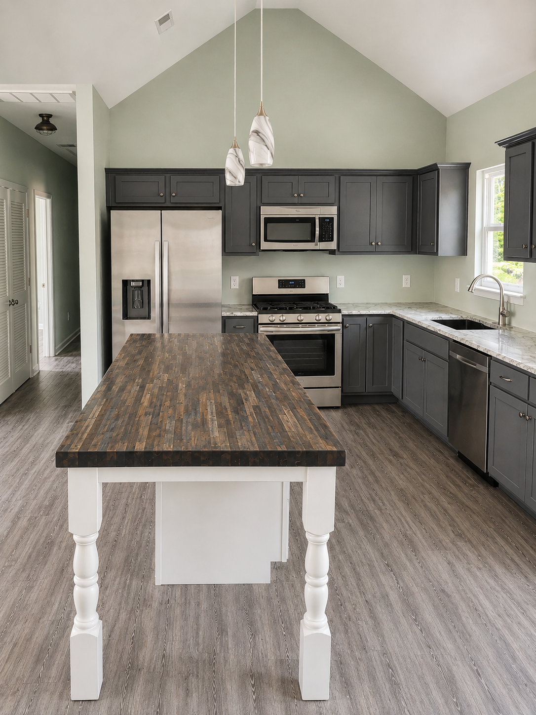 Modern kitchen with gray cabinets, stainless appliances, and a large island with dark wood countertop