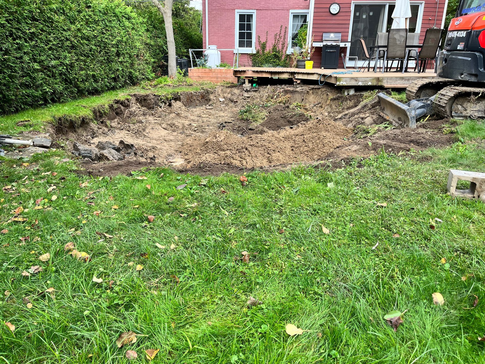 Un gros tas de terre se trouve au milieu d'une pelouse verte luxuriante devant une maison.