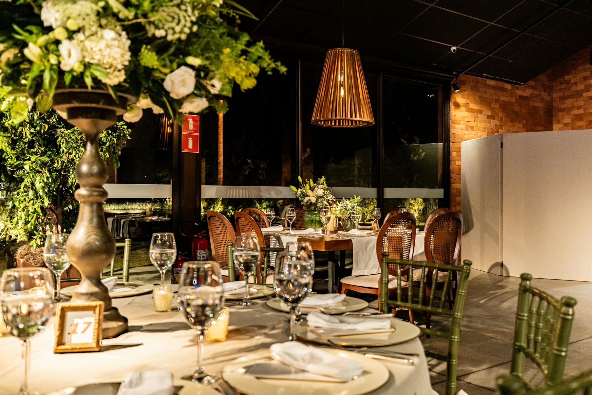 Elegant dinner table set with white flowers, candles, and green chairs in a warmly lit restaurant