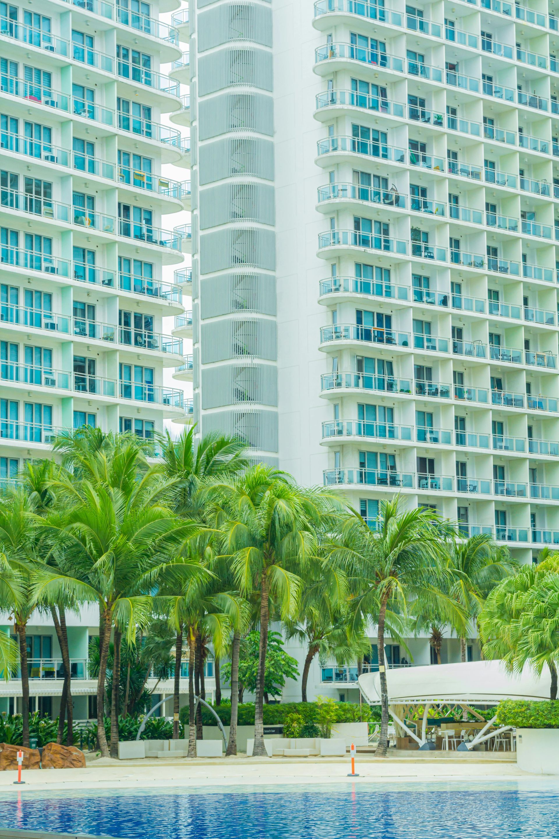High-rise beachfront condo with palm trees and a pool in the foreground