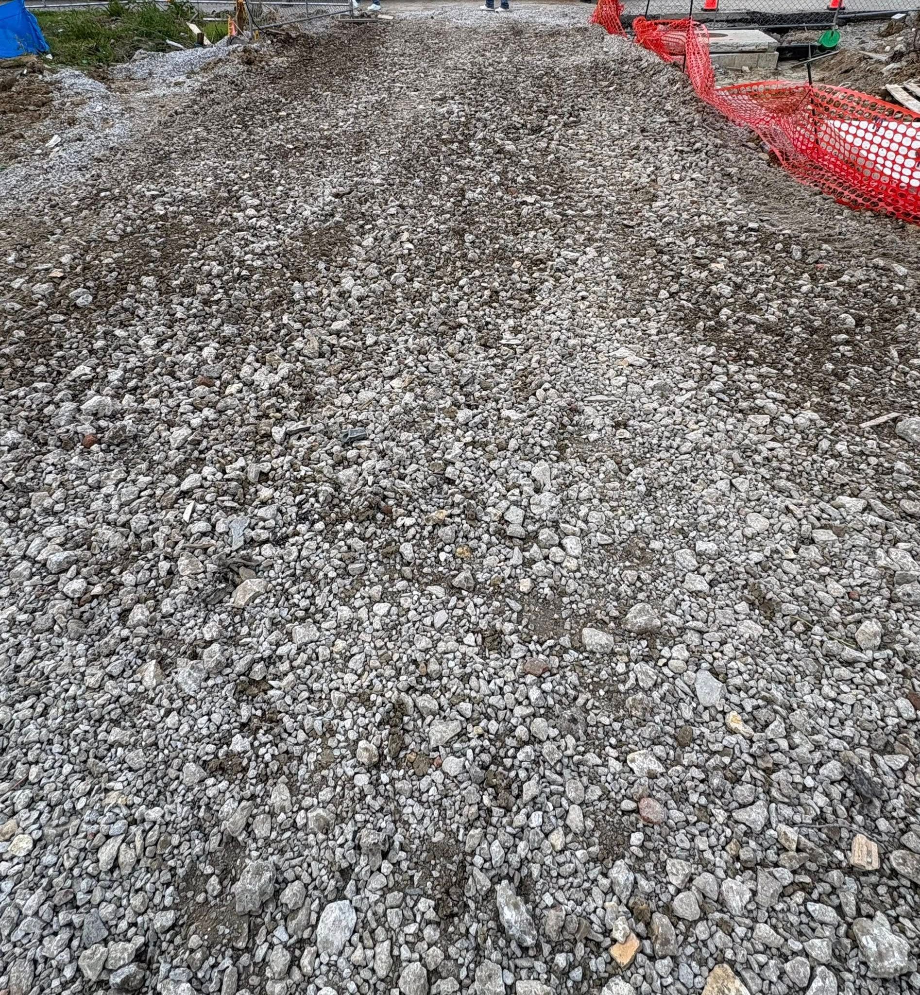 Gravel mound beside a red safety fence at a construction site
