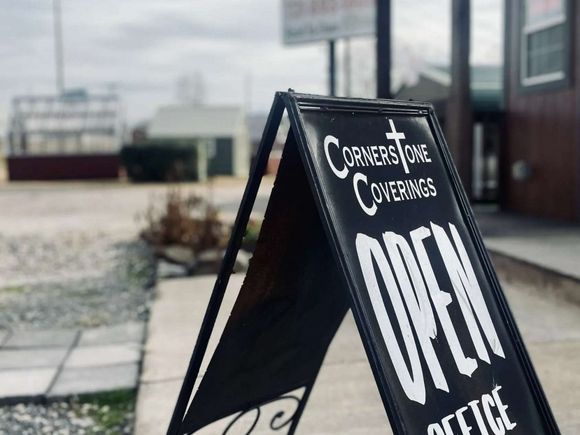 Black sandwich board sign outside a storefront, with “OPEN” in white letters.