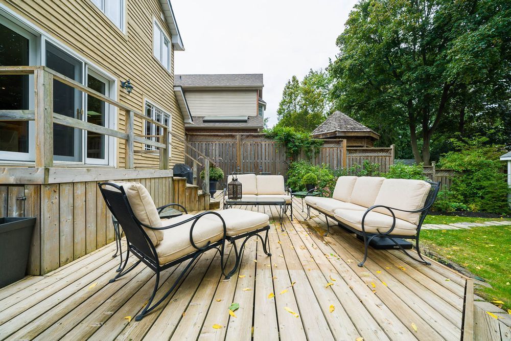 Wooden deck with patio furniture, next to a wood-sided house and green lawn.