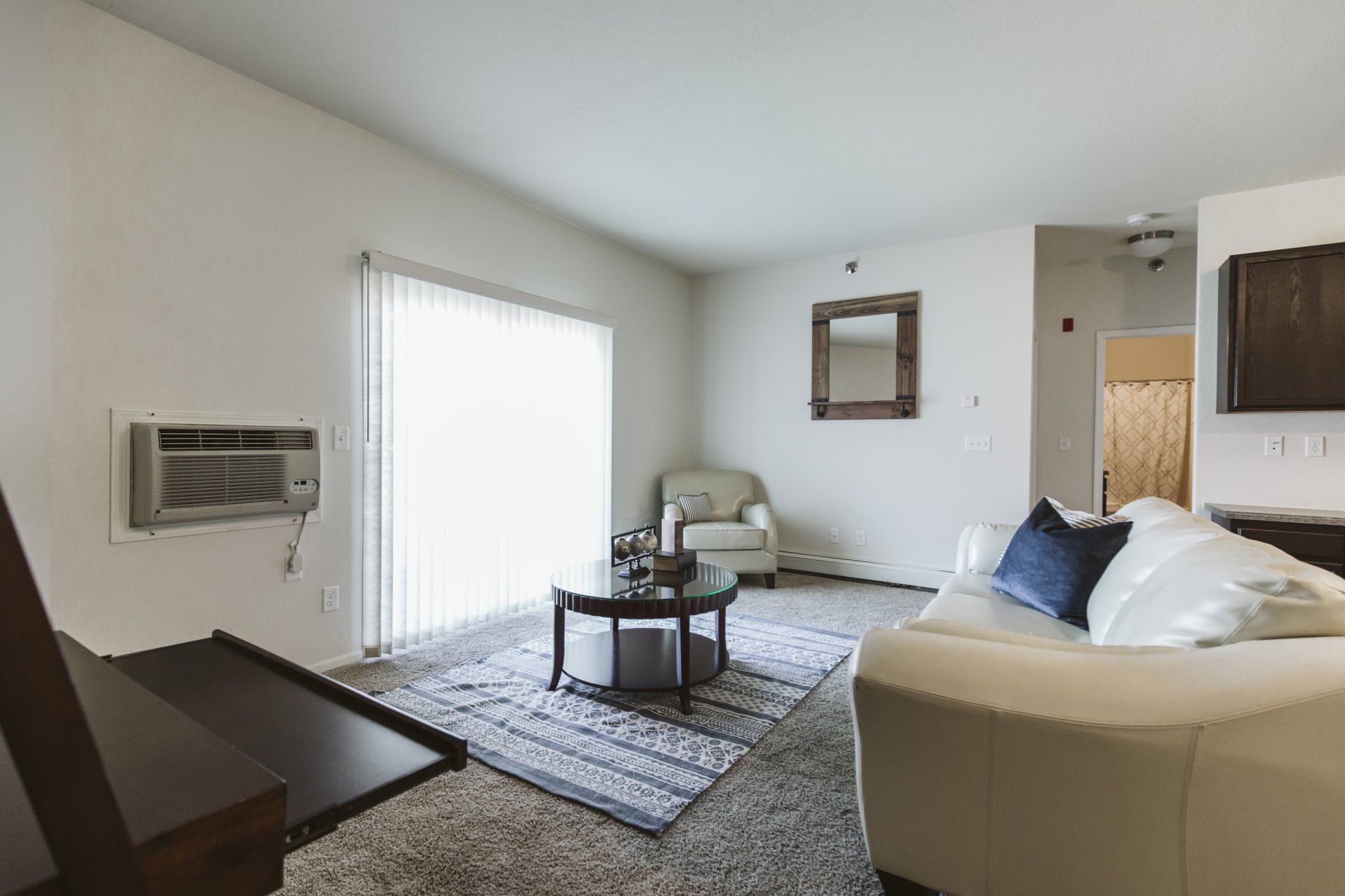Carpeted living room with large sliding glass door leading to balcony