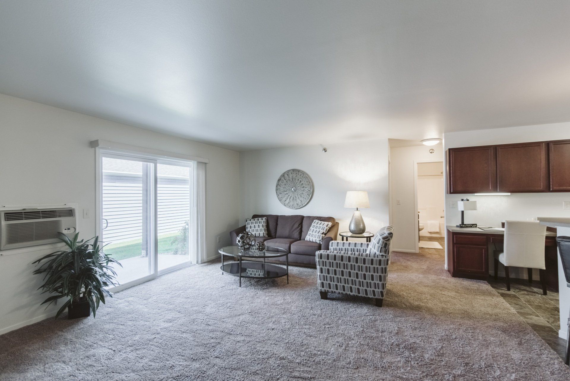 Living room with sofa, chair, carpeted flooring, and large sliding glass doors leading to balcony