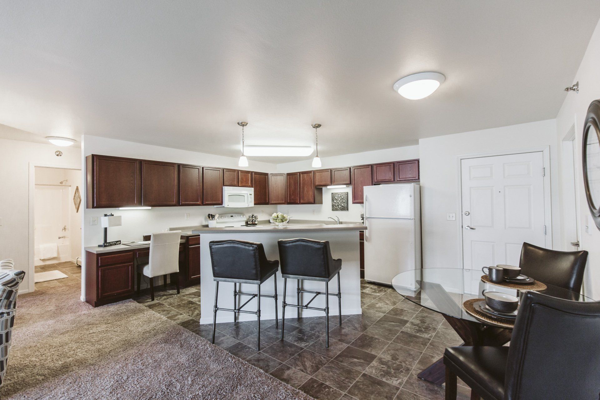 Kitchen island with two bar stools and tile flooring in kitchen