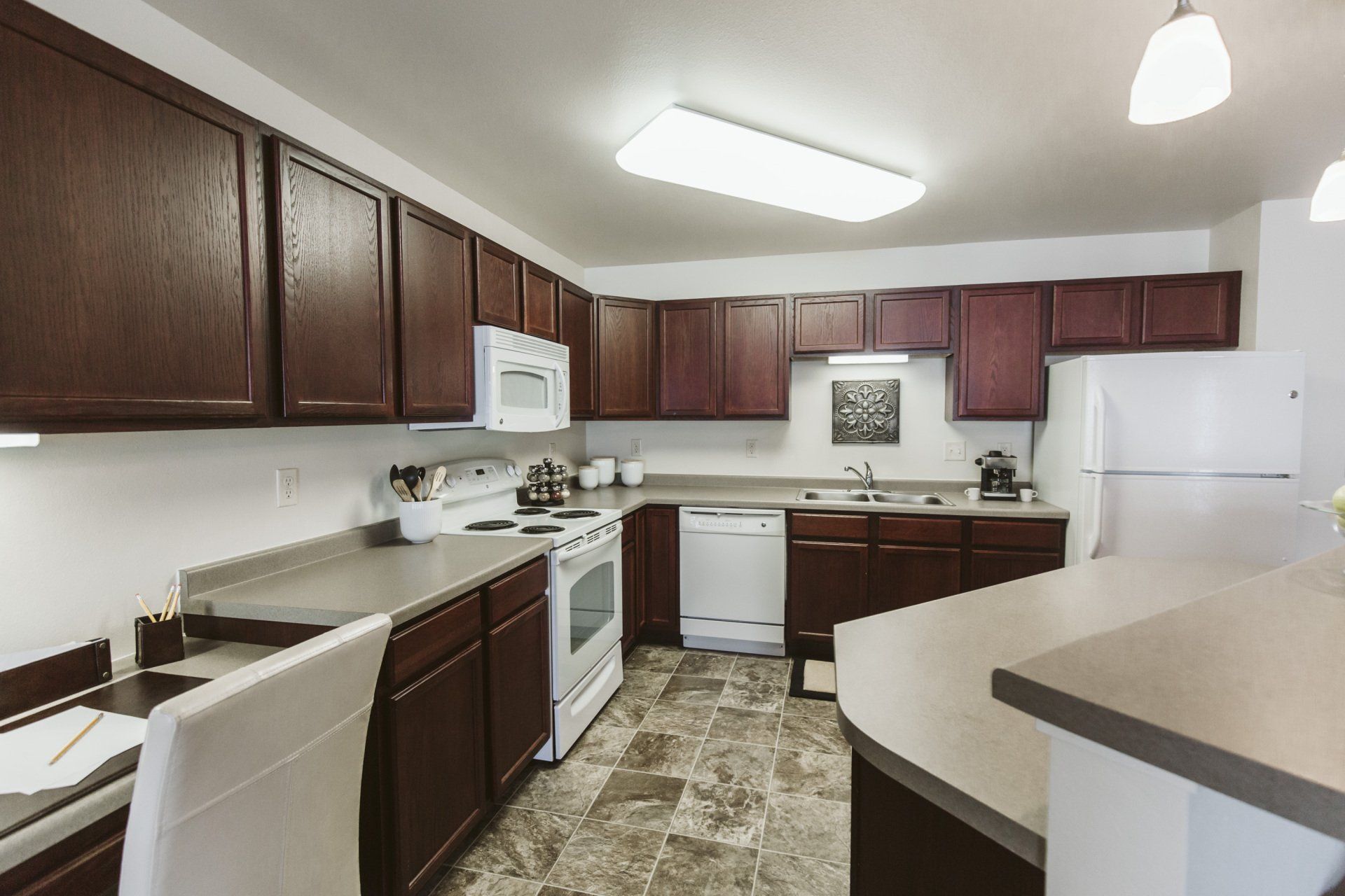 Large kitchen with dark wood cabinetry and white appliances