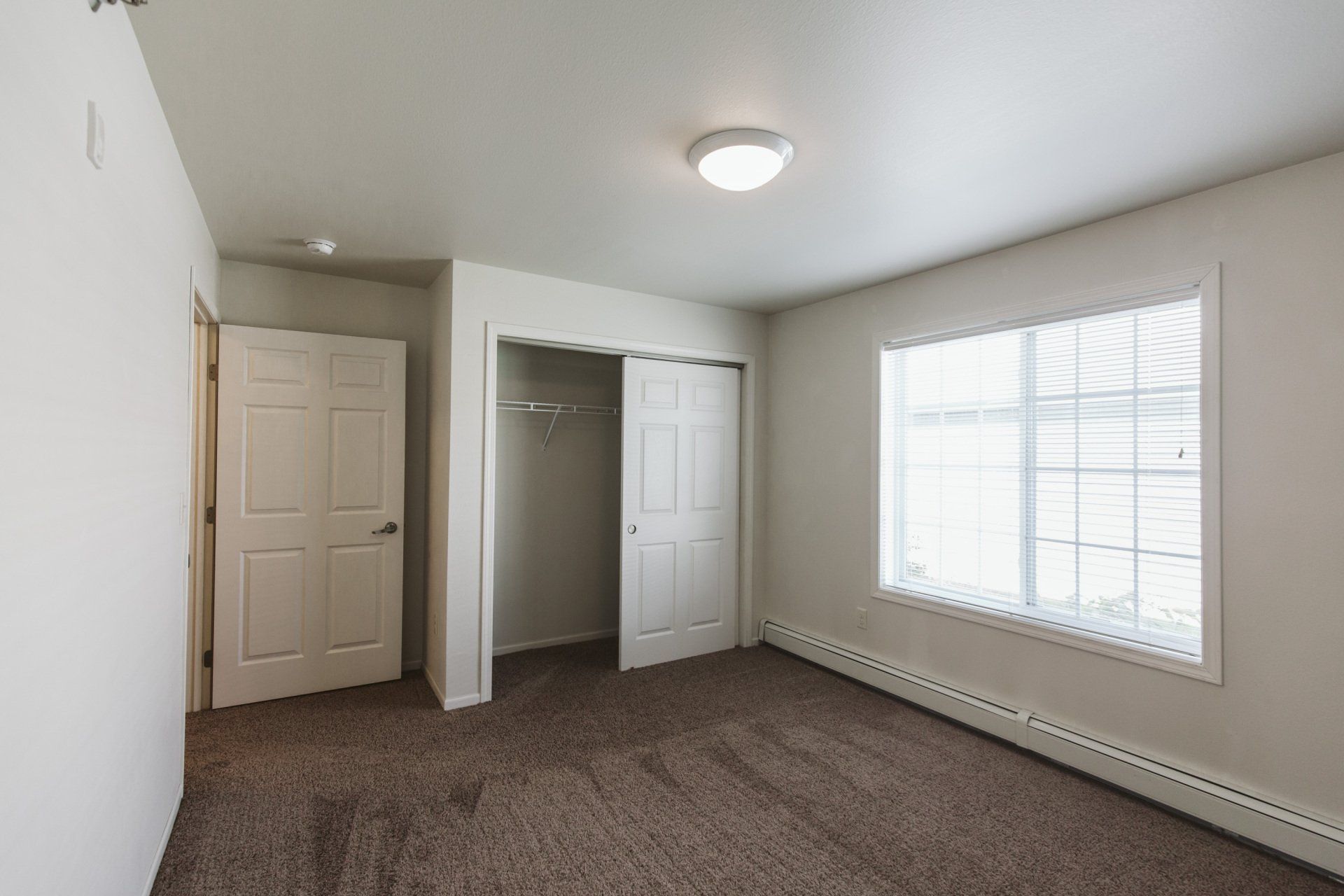 Alternate view of carpeted bedroom with large sliding door closet and window