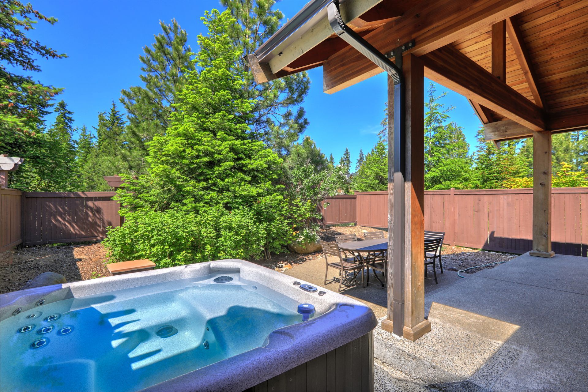 Hot tub on a patio with a covered seating area. 