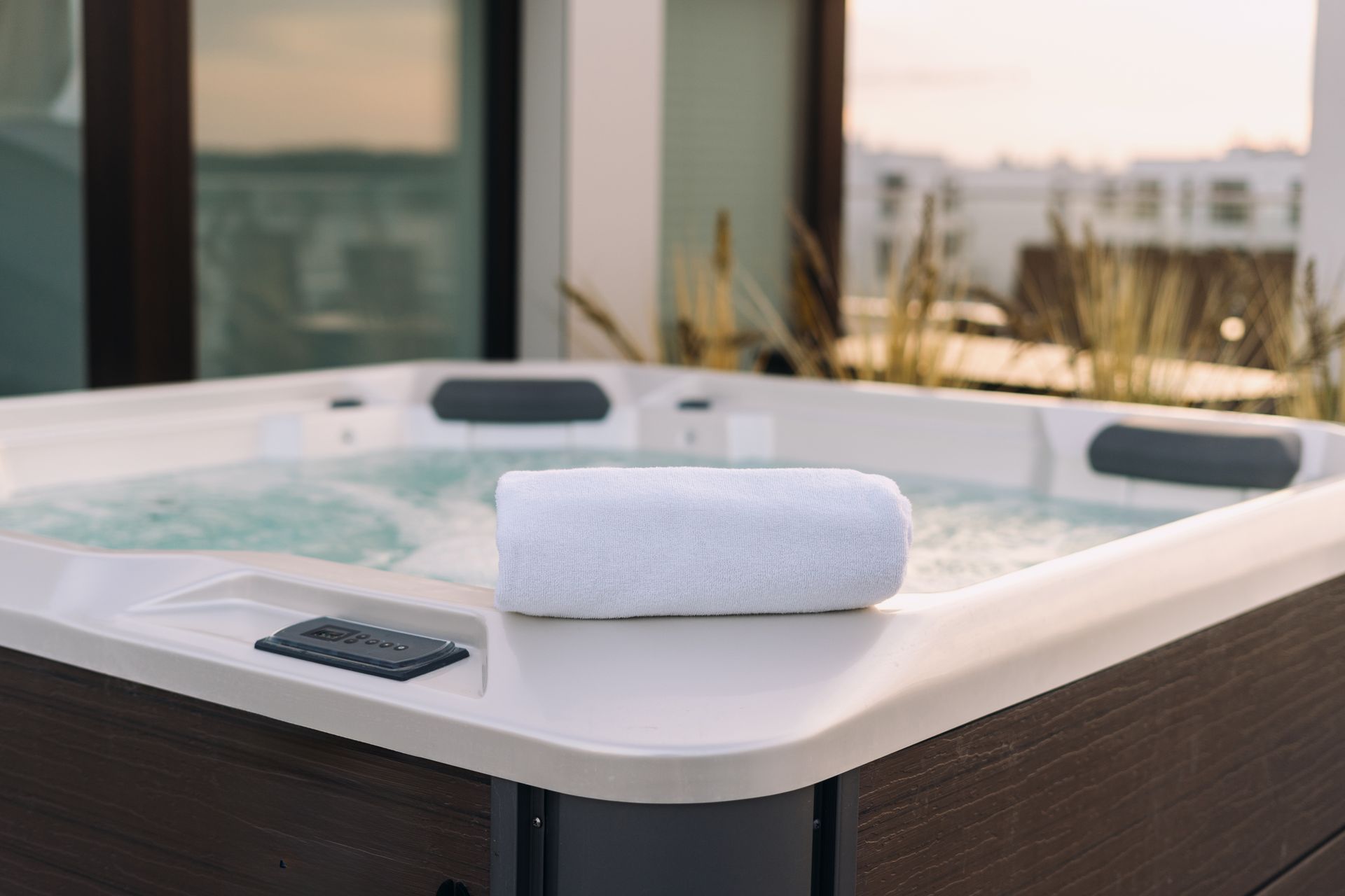 Hot tub on a rooftop with a rolled white towel; sunset view.