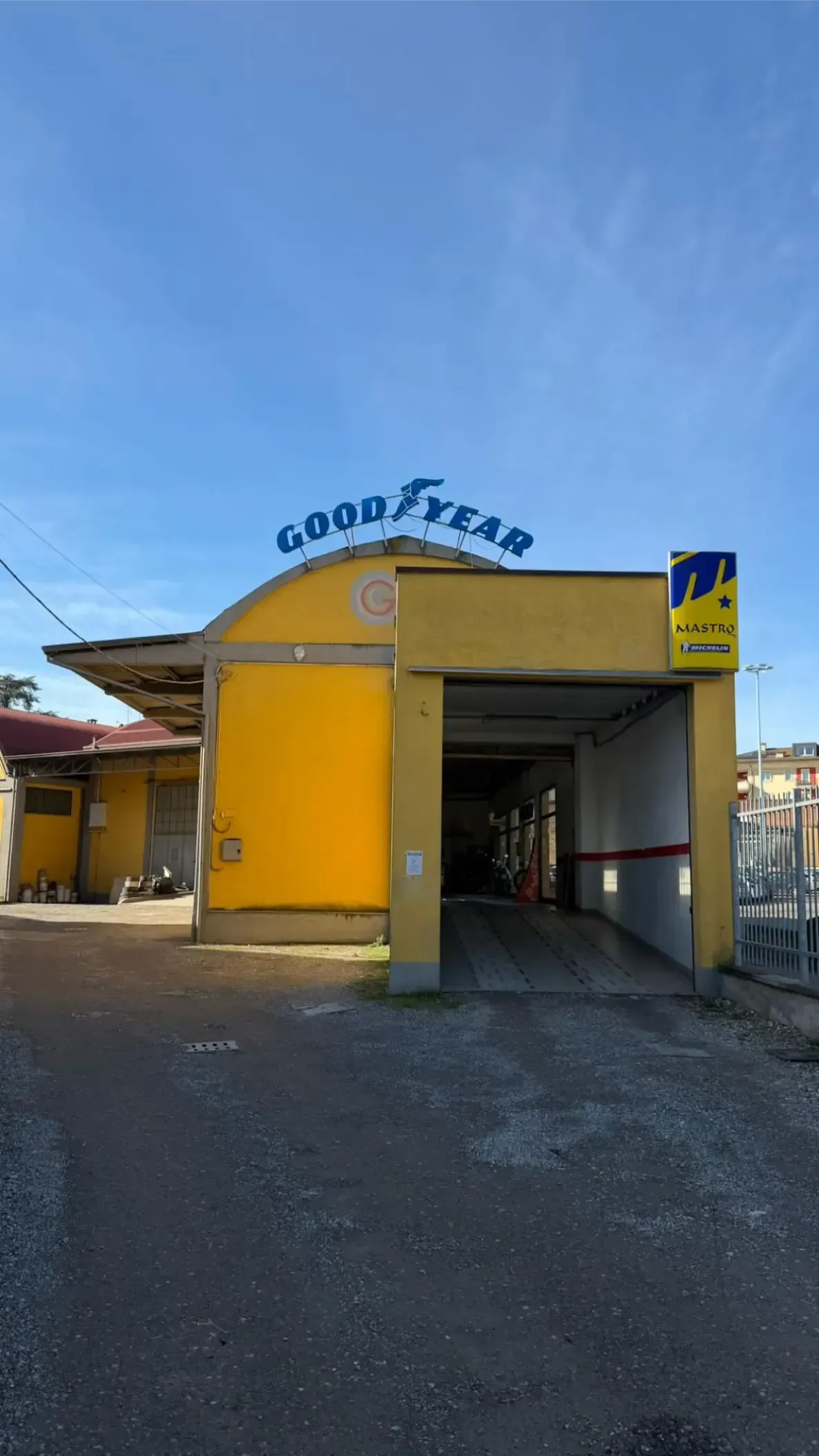 Un SUV bianco su un ponte sollevatore rosso viene riparato da un meccanico in un'officina.