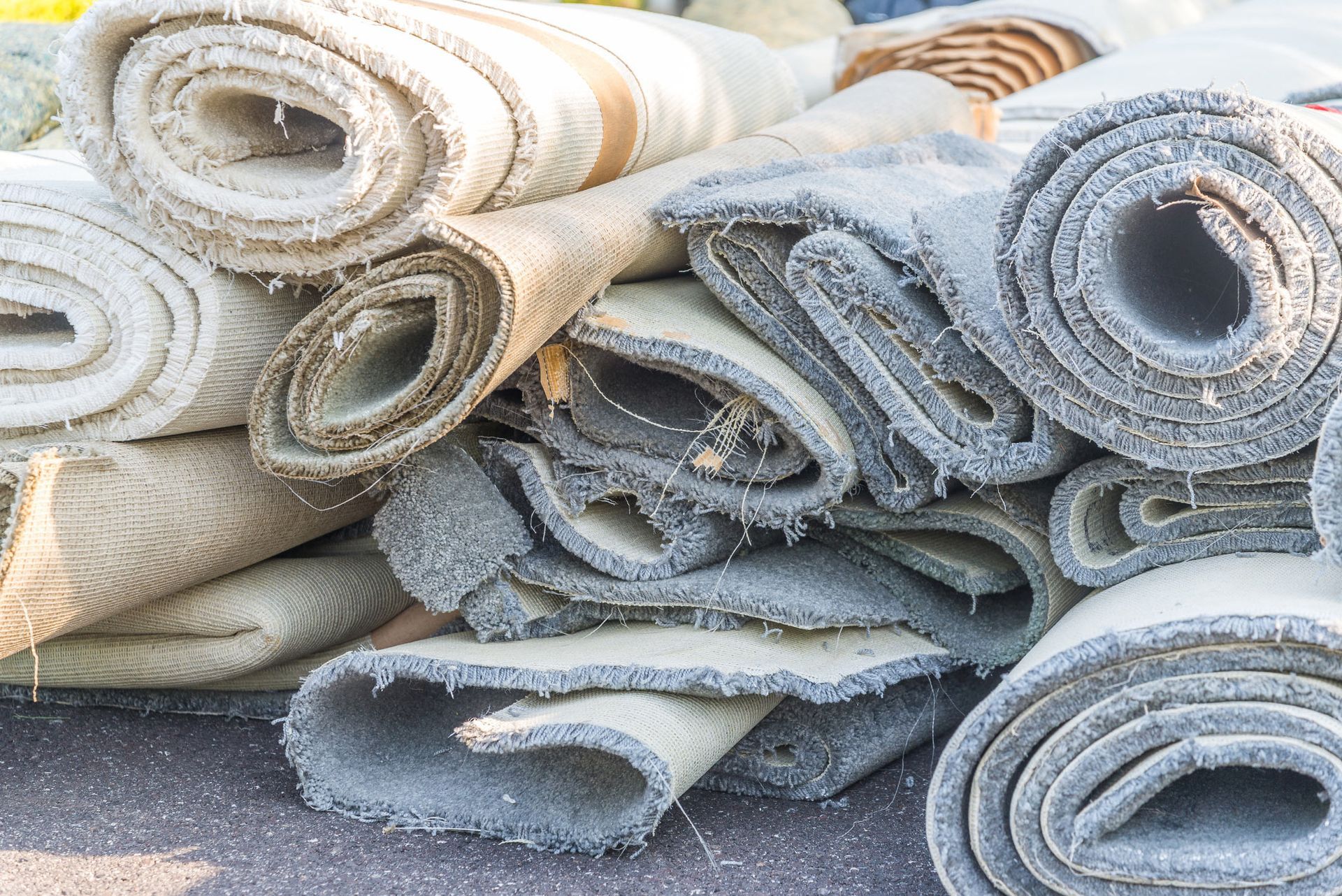 A pile of rolled up carpets on the ground.