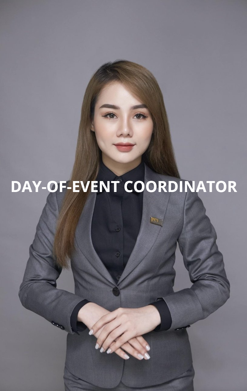 A woman in a suit is standing with her hands folded.