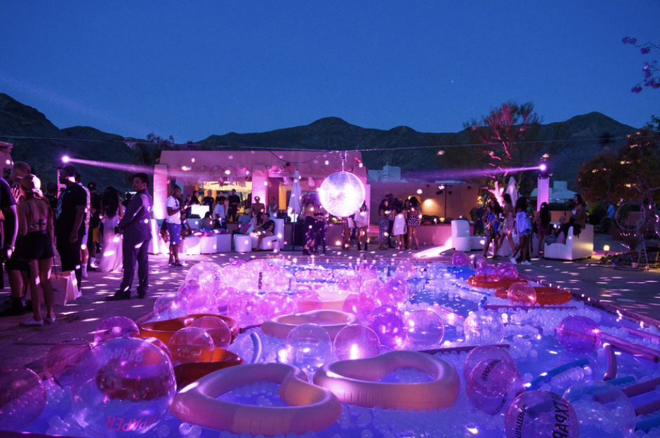 A group of people are standing around a pool filled with floats and a disco ball