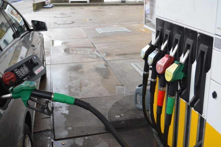 Ein Auto wird an einer Tankstelle betankt; die Zapfsäule verfügt über mehrere farbige Zapfpistolen.