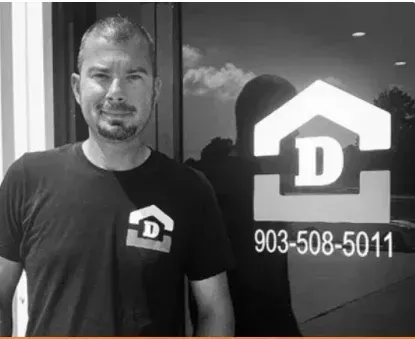 Man standing by a glass door with a D logo and phone number 903-508-5011