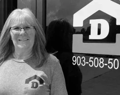 Woman standing beside a business sign with a large “D” logo and phone number 903-508-50.