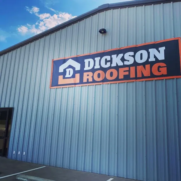 Dickson Roofing sign on a blue metal building under a partly cloudy sky