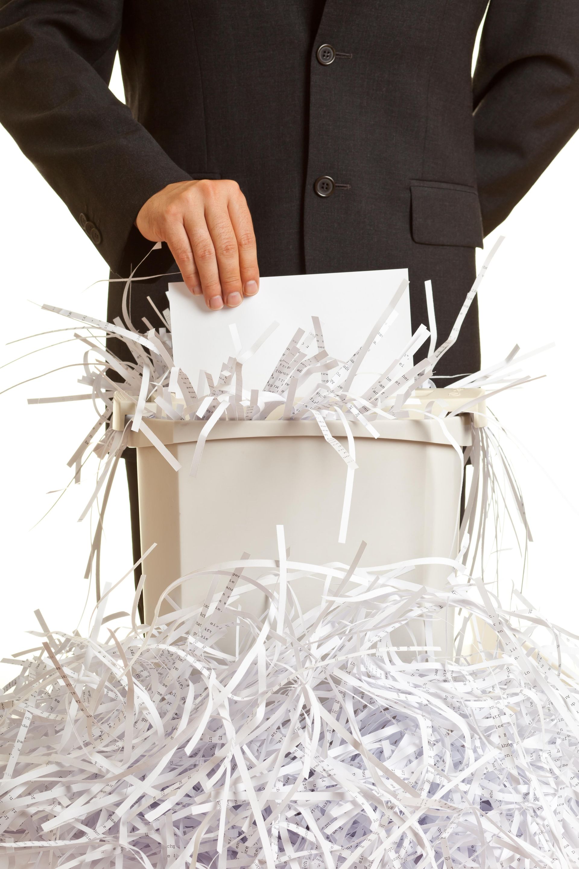 a man in a suit is putting a piece of paper in a box of shredded paper