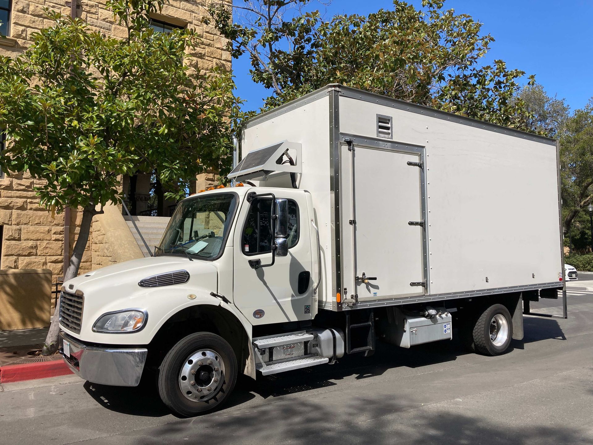 a white truck is parked on the side of the road in front of a building