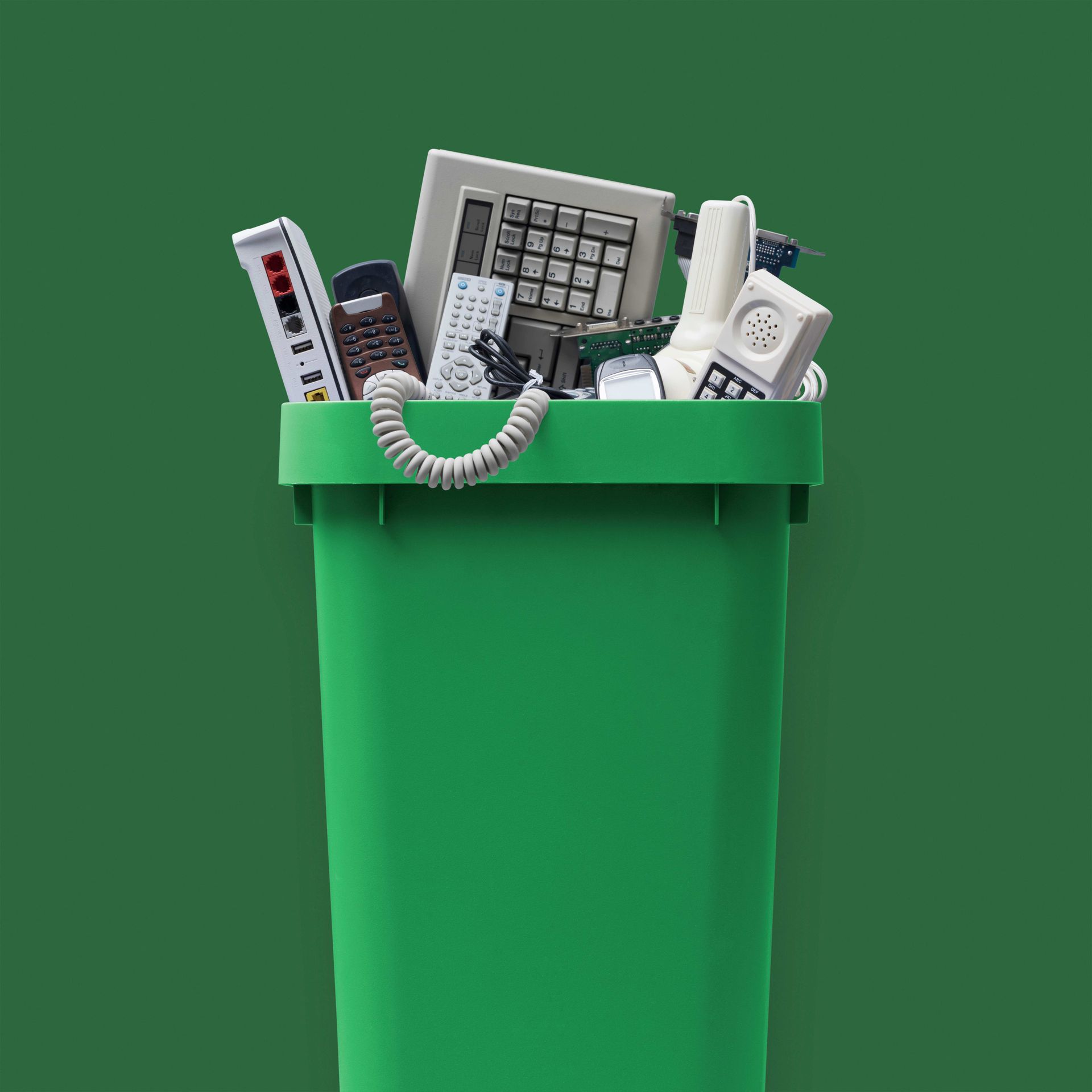 a green trash can filled with electronic waste on a green background
