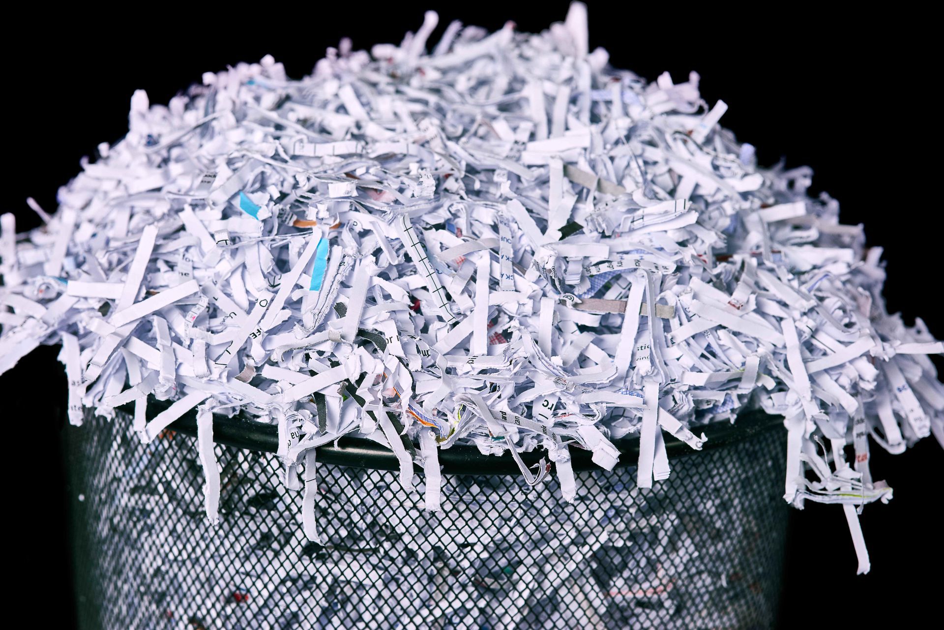 a trash can filled with shredded paper on a black background