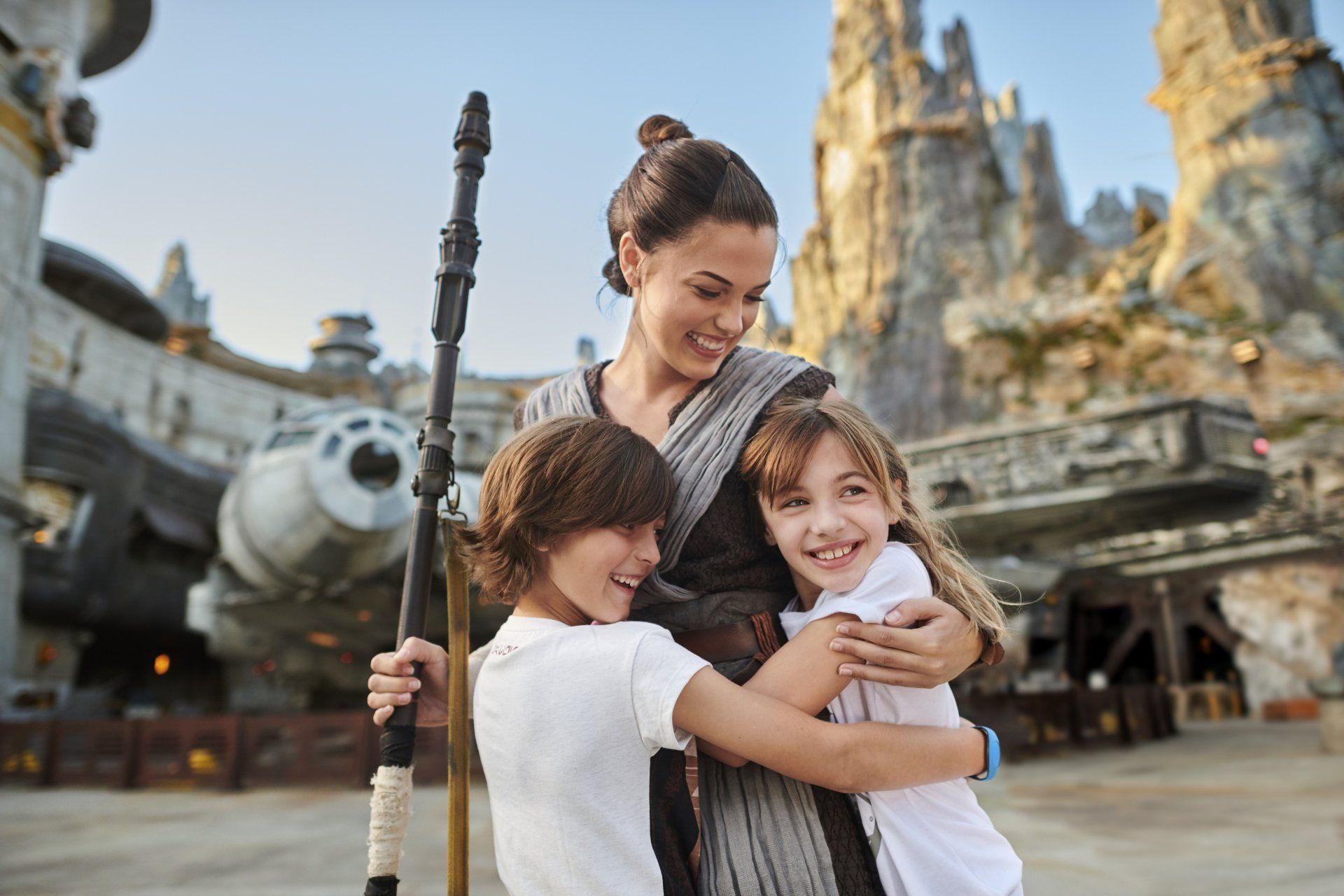 A woman is holding two children in her arms in front of a castle.