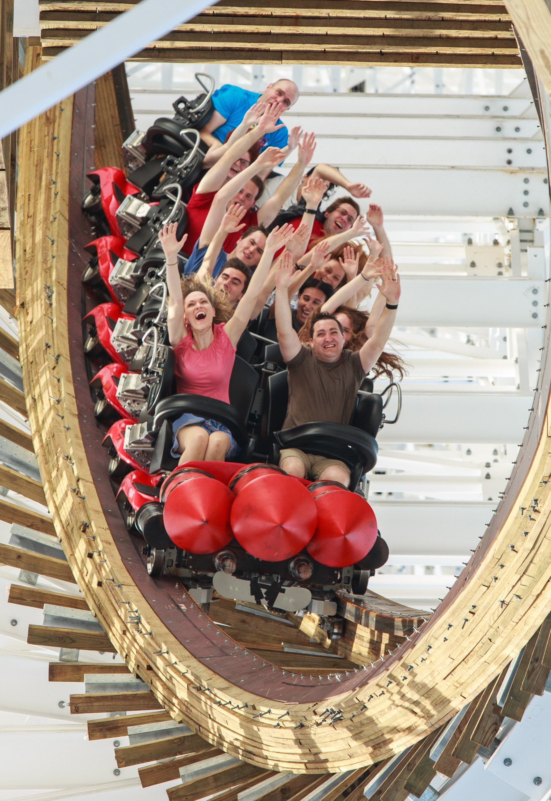 A group of people are riding a roller coaster with their arms in the air.