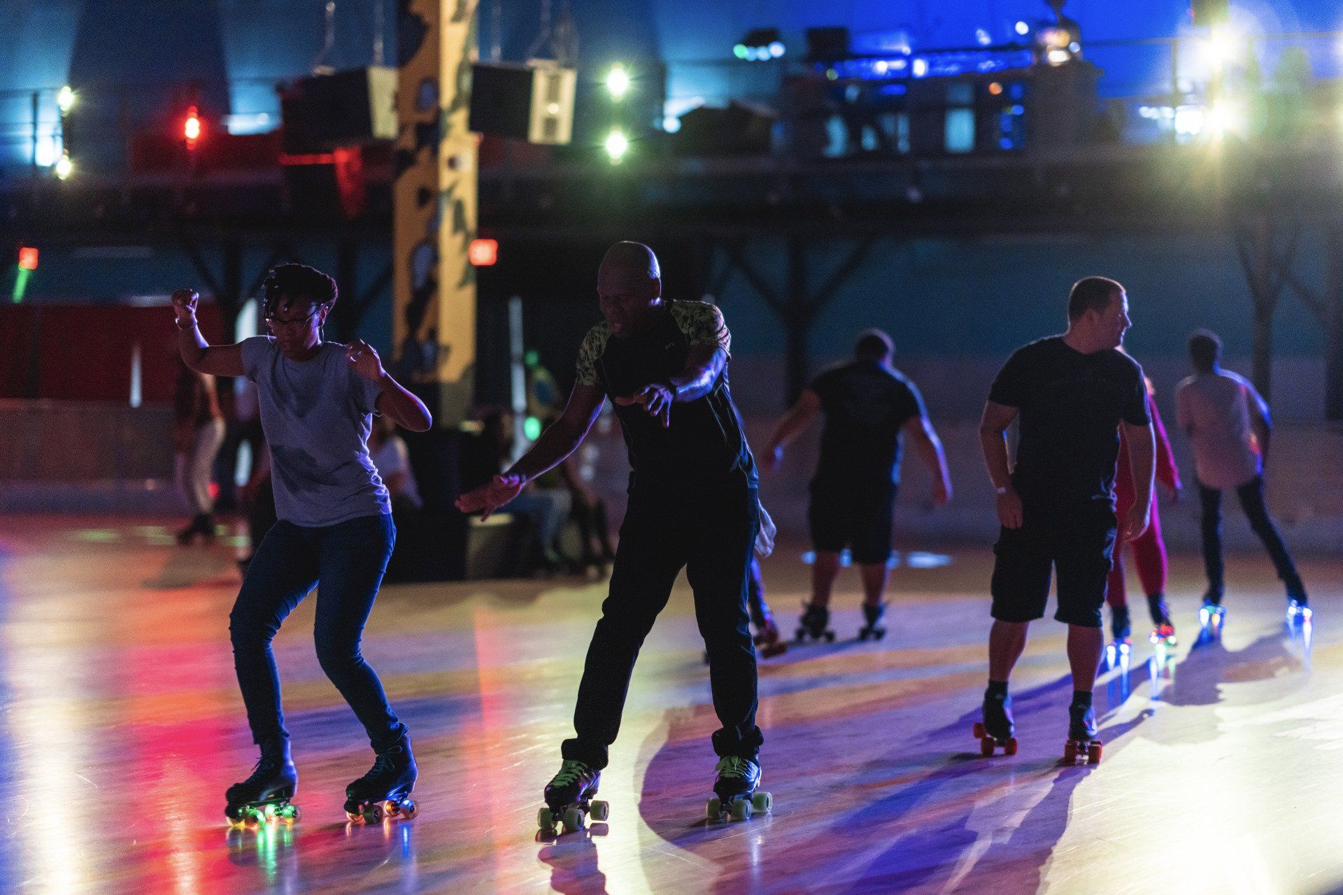 A group of people are rollerblading on a rink at night.