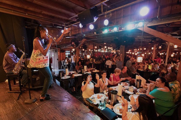 A woman is singing into a microphone on a stage in front of a crowd of people.