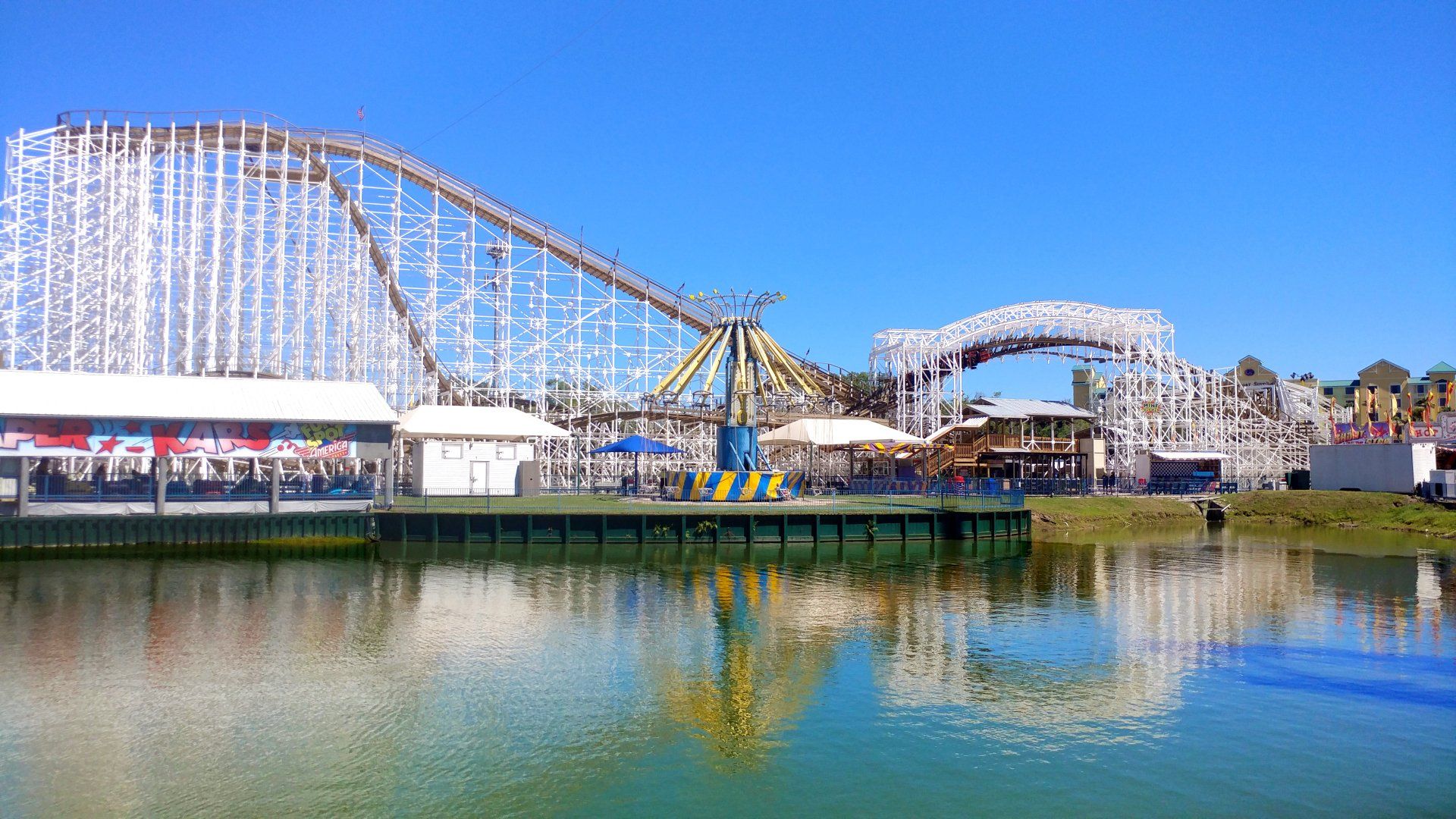 A roller coaster is reflected in the water at an amusement park.