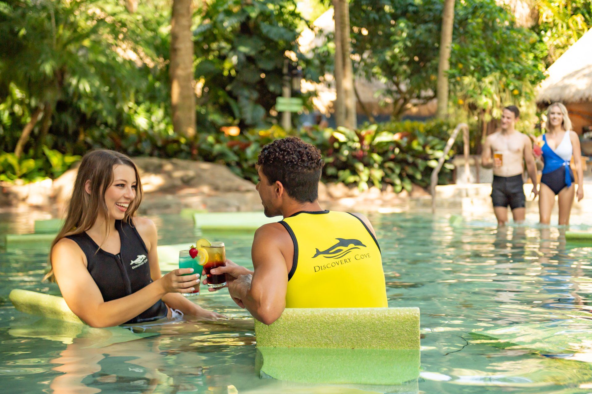 A man and a woman are drinking cocktails in a swimming pool.