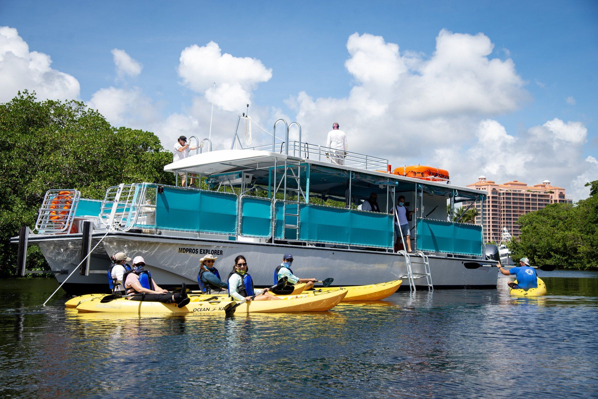 A group of people in kayaks are sitting on a boat in the water.