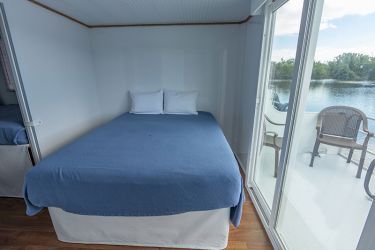 There is a bed in the middle of the room with a view of the water.