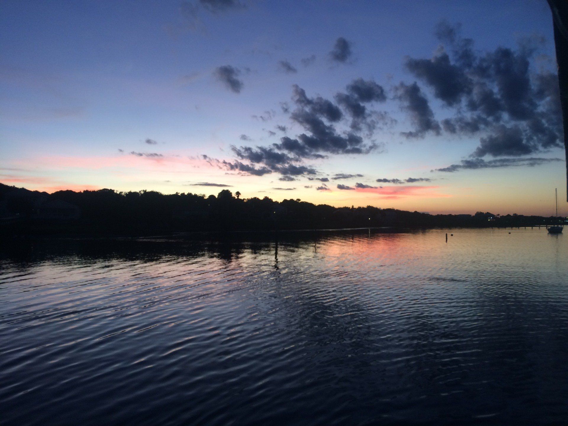 A sunset over a body of water with trees in the background.