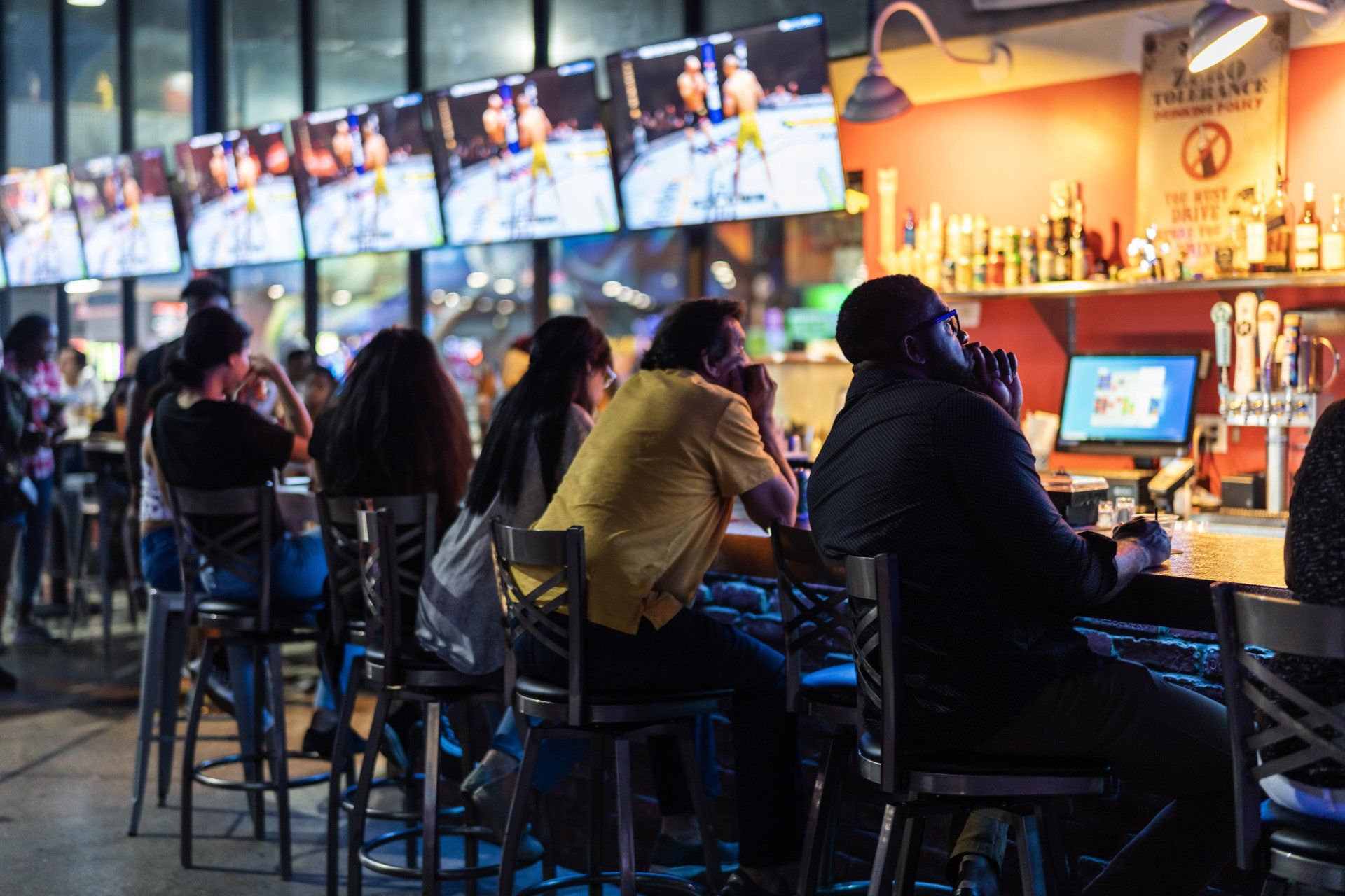 A group of people are sitting at a bar in a restaurant.