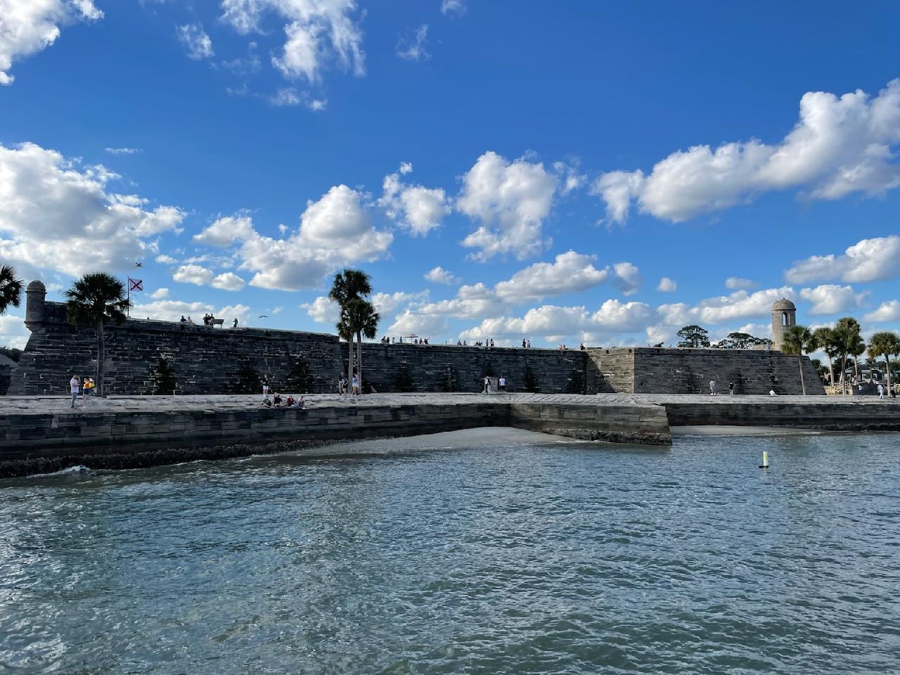 A large stone wall surrounds a body of water.