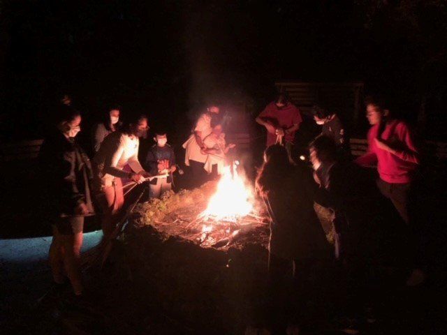 A group of people are gathered around a campfire at night.