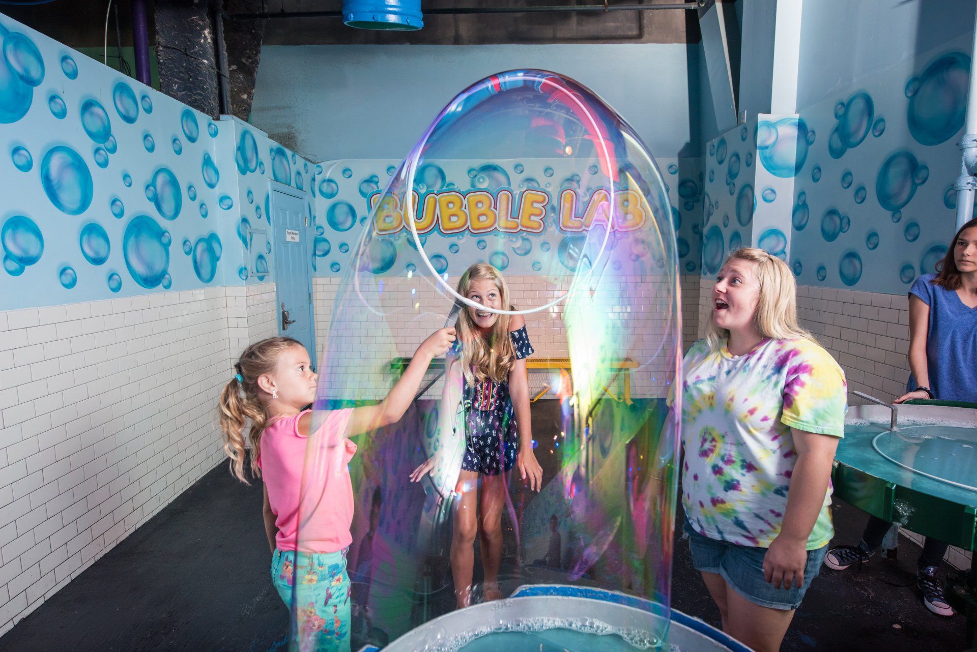 A group of children are blowing soap bubbles in a room.