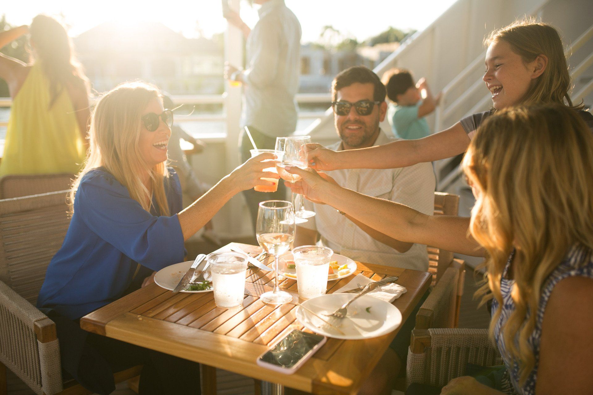 A group of people are sitting at a table toasting with wine glasses.