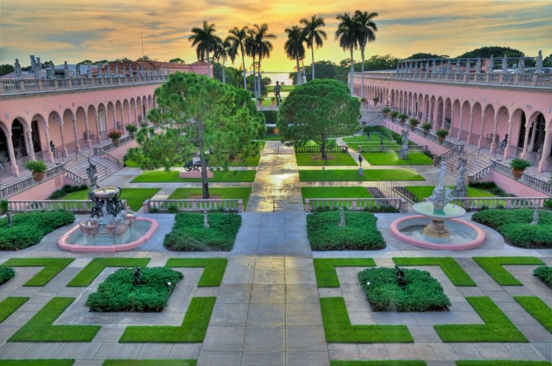 An aerial view of a lush green garden with palm trees in the background