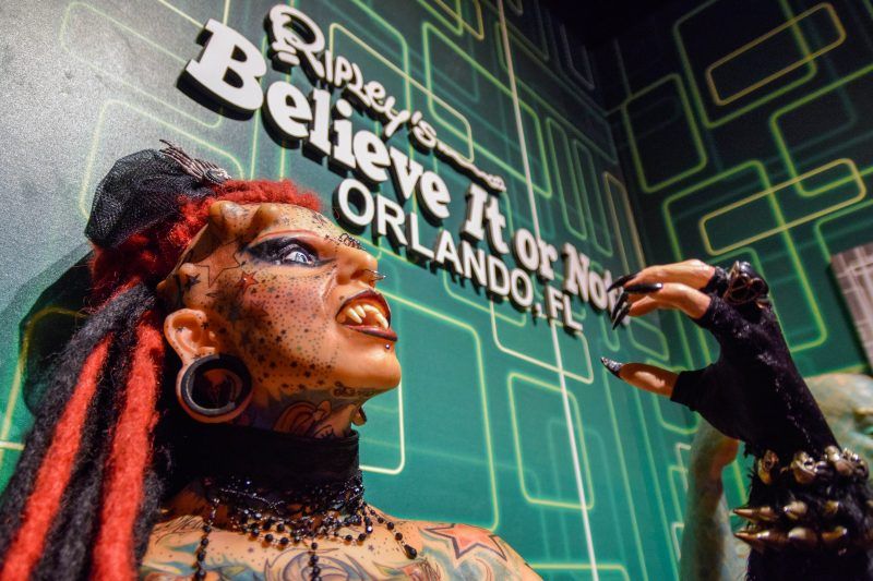 A statue of a woman is standing in front of a sign that says believe it or not