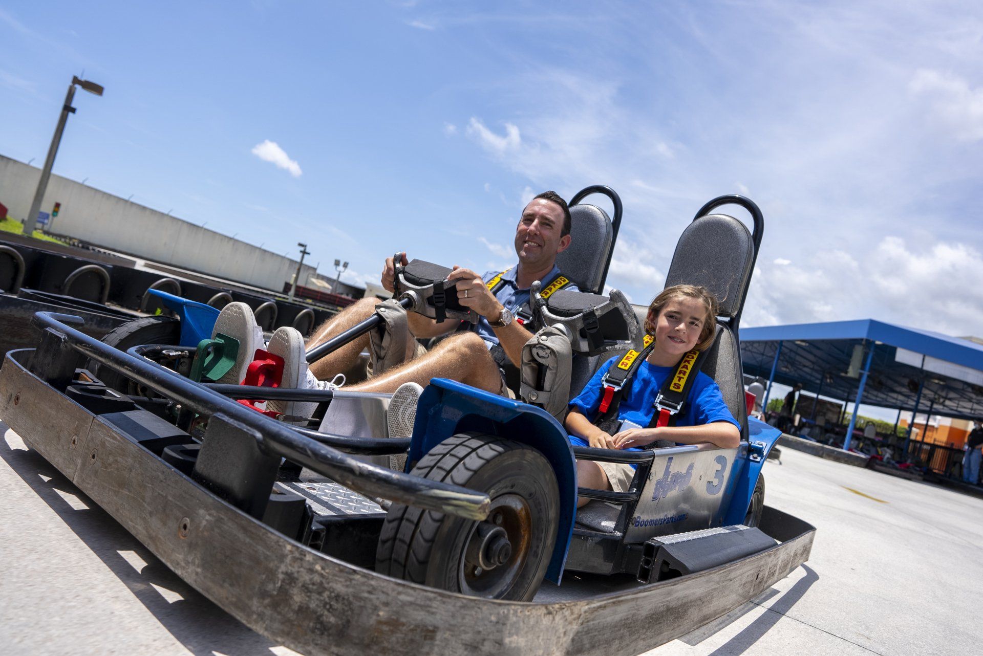 A man and a child are riding a go kart on a track.