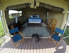 A tent with a bed and chairs inside of it.
