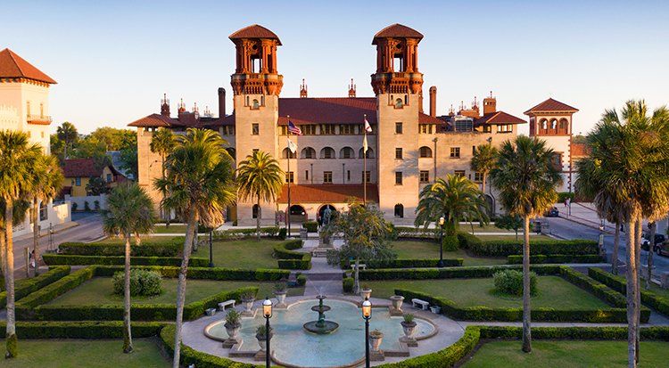 An aerial view of a large building with a fountain in front of it.