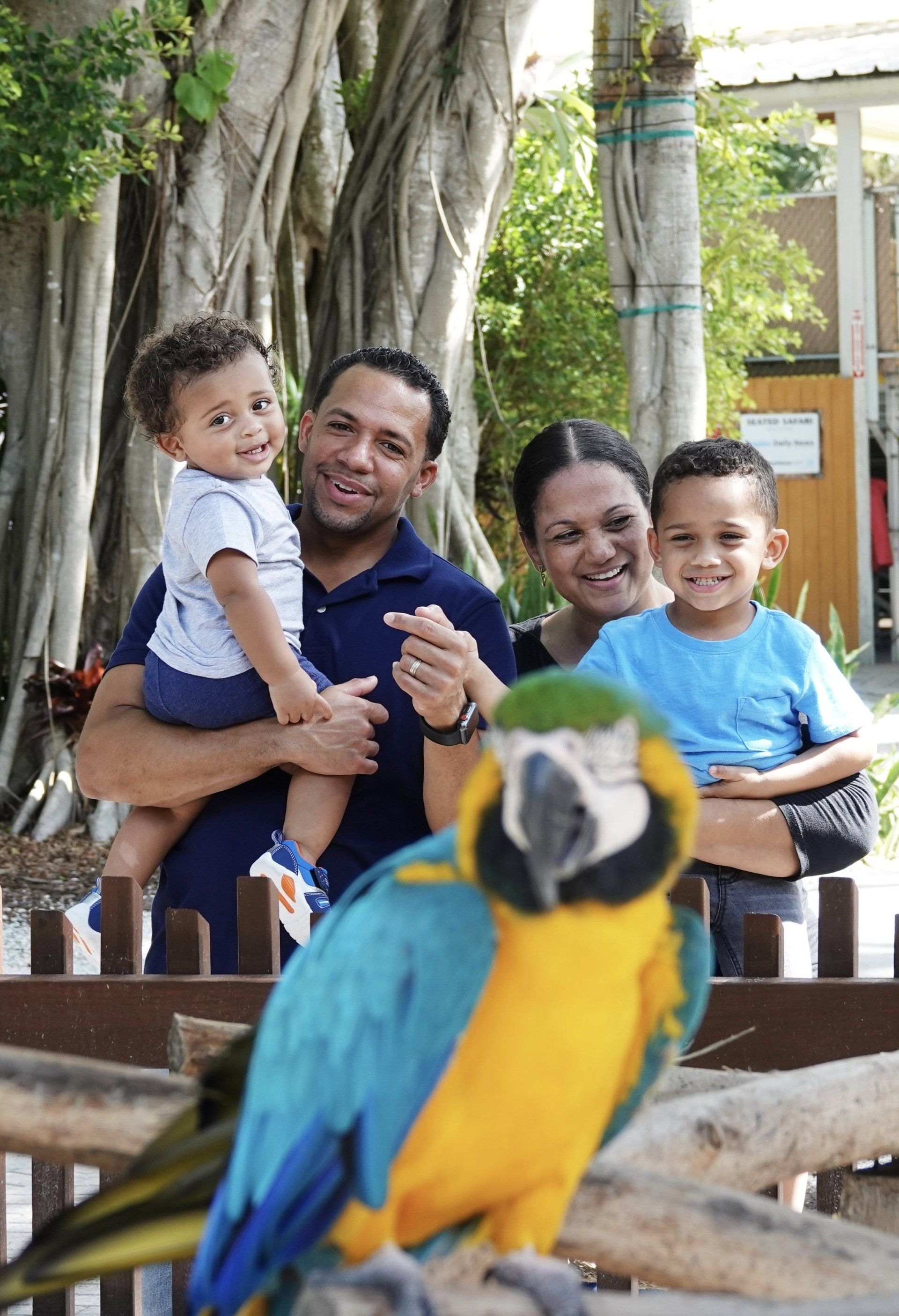 A family standing next to a blue and yellow parrot