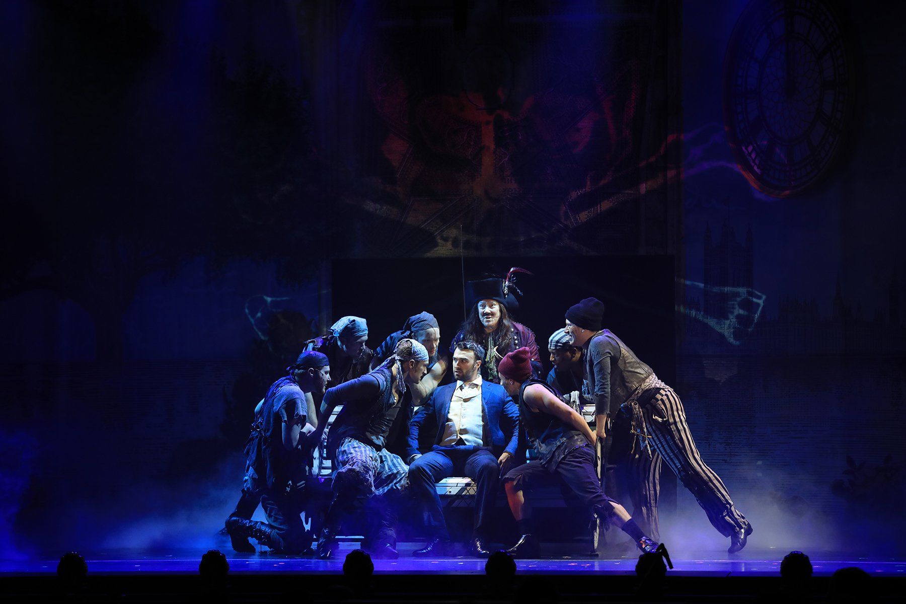 A group of people are standing around a man on a stage.